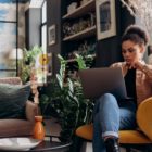 Woman in Brown Jacket Sitting on Armchair while Using Her Laptop